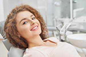 Woman in pink shirt leaning back in treatment chair and smiling